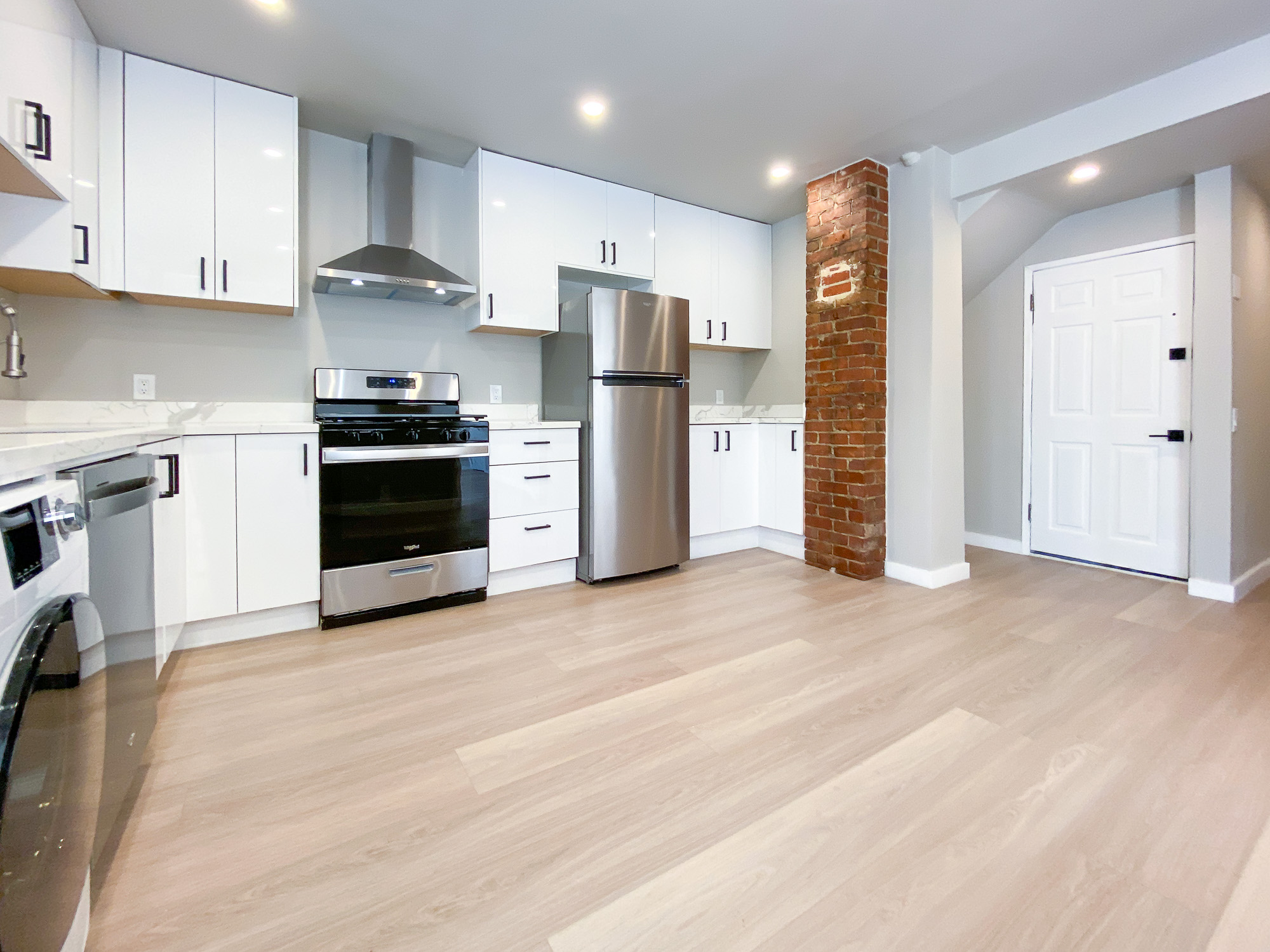 Open kitchen with stainless steel appliances and white oak floors